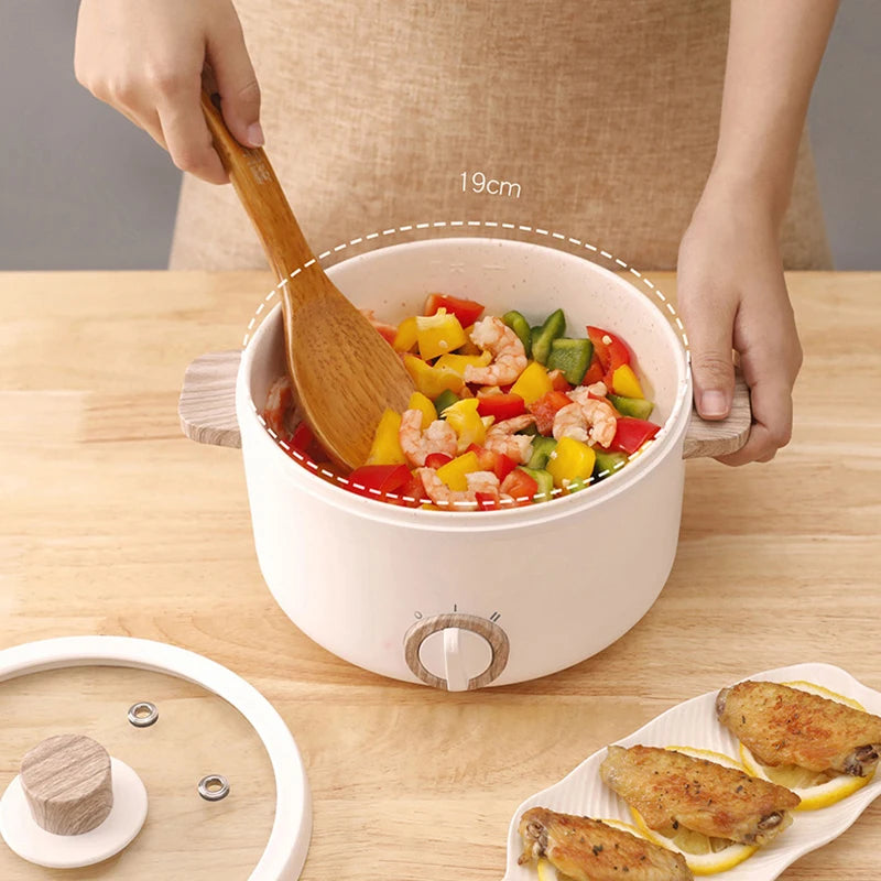 Multi-function Mini Cooker cooking shrimp stir-fry with vegetables, next to fried chicken wings and a transparent lid on the side.