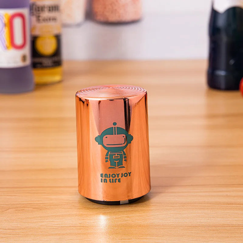 Single copper can opener with deer design on a wooden surface, with beverage bottles in the background.