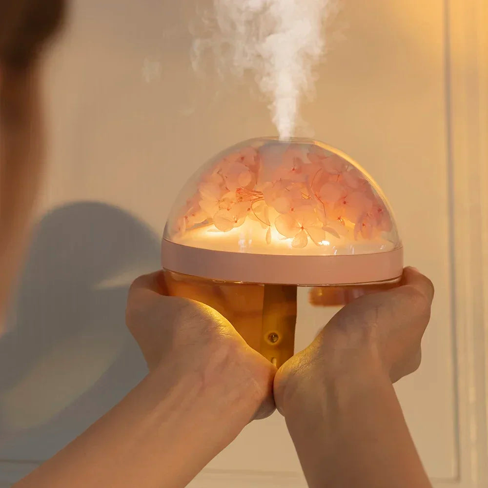 Person holding a glowing pink and white diffuser emitting steam.