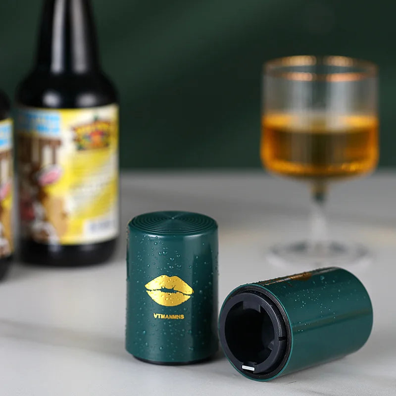 Green automatic beer opener on table with glass of beer and bottles in background