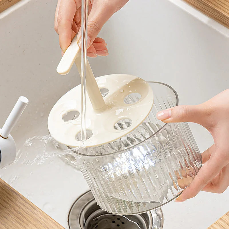  Hands rinsing the Meatball Maker under a faucet, demonstrating its easy cleaning process over a kitchen sink.