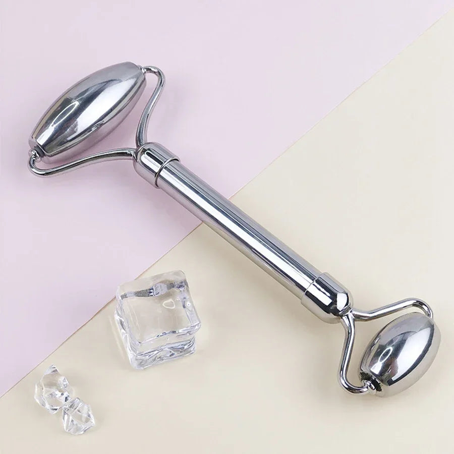 Metal facial roller on a light pink background