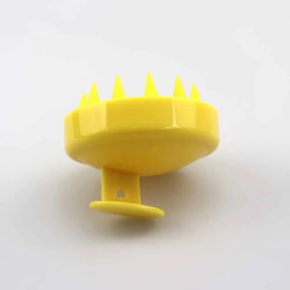 Yellow scalp brush massager on a towel